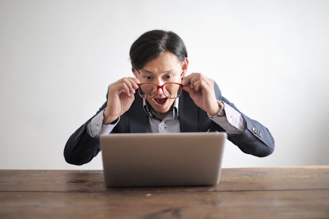 A man in a suit focused on his laptop, highlighting the role of CRM in identifying potential risks