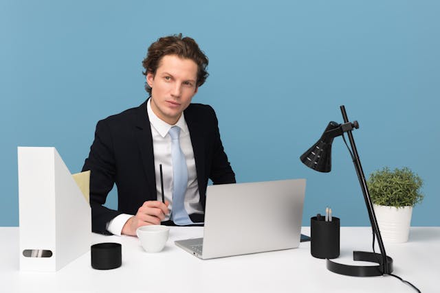 A man in a suit sitting at a desk with a laptop, focusing on risk management CRM